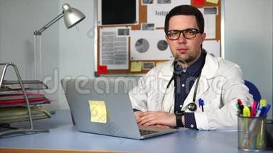 穿着白色外套的医生坐在<strong>柜子</strong>里，在他的笔记本电脑上工作。